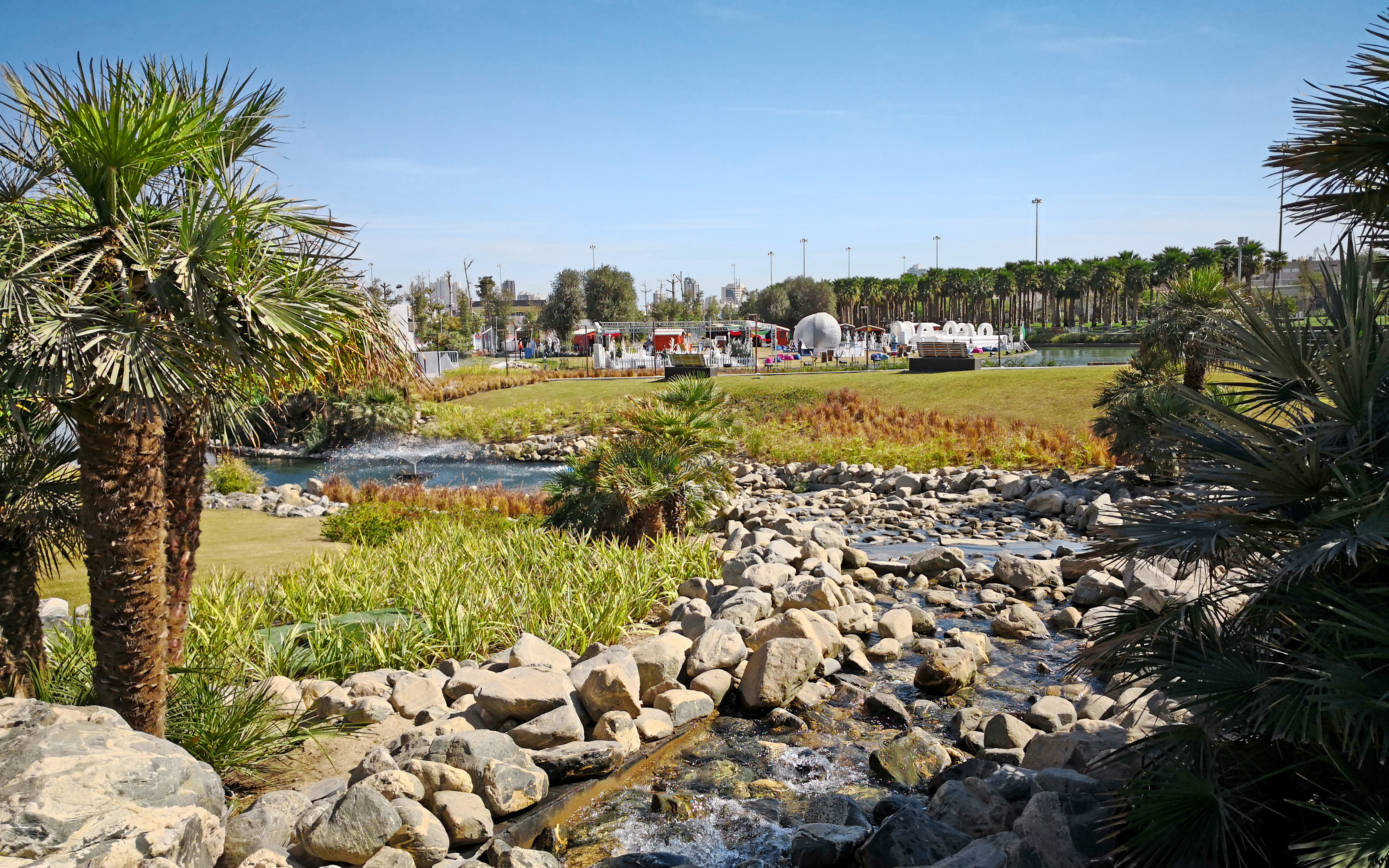 The focus is set clearly on native plants which are ideal for the arid location. Water course in a park with palm trees
